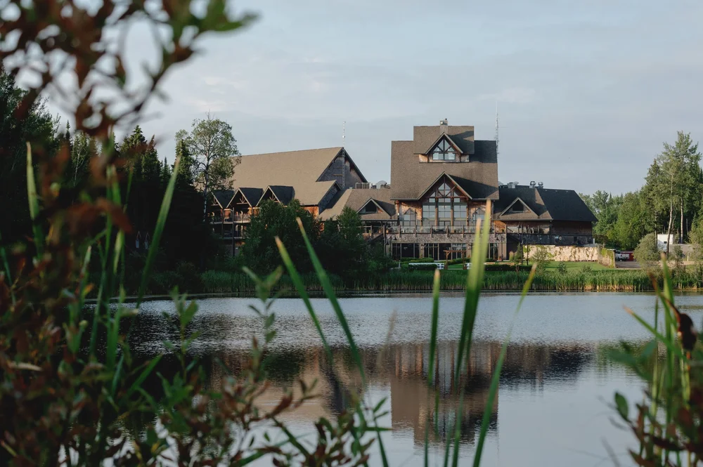 A large lodge-style building with multiple gables reflected in the water