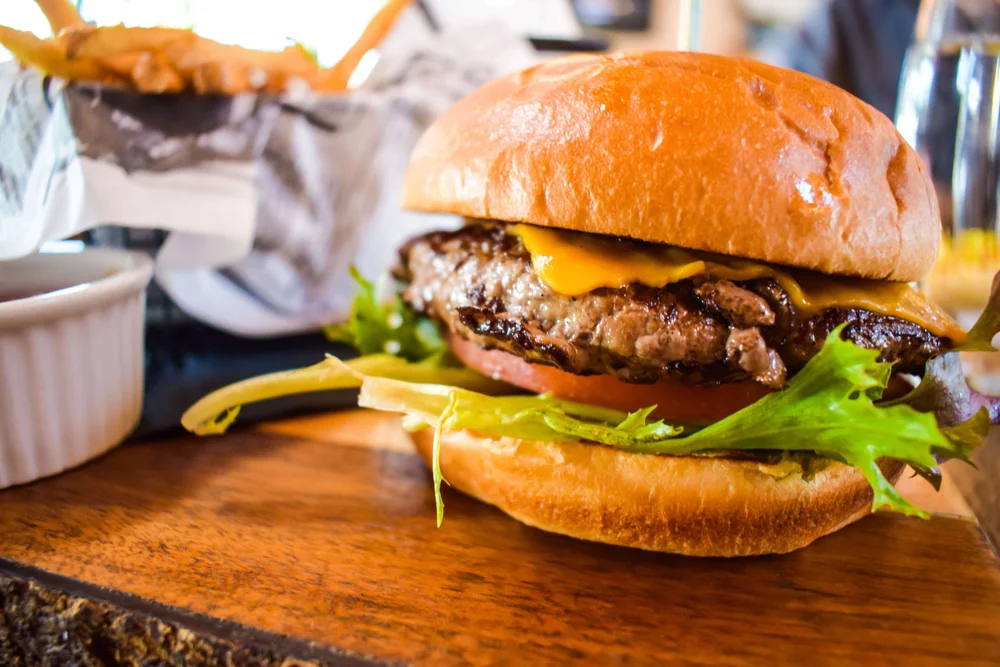 Close-up of a cheeseburger with lettuce, tomato and pickle