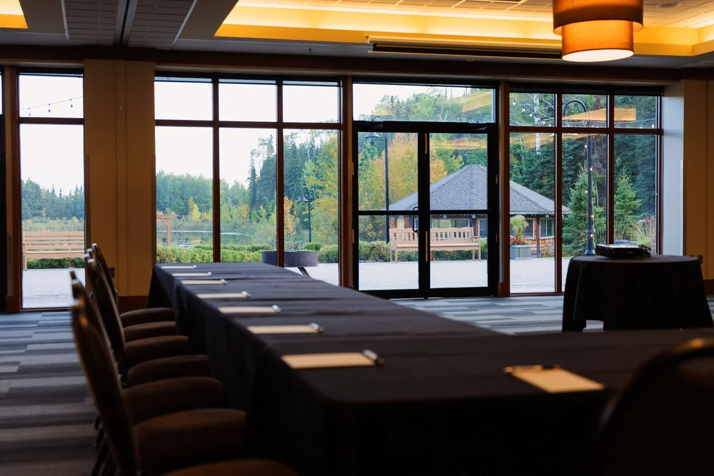 A meeting room with long tables and large windows onto the forest