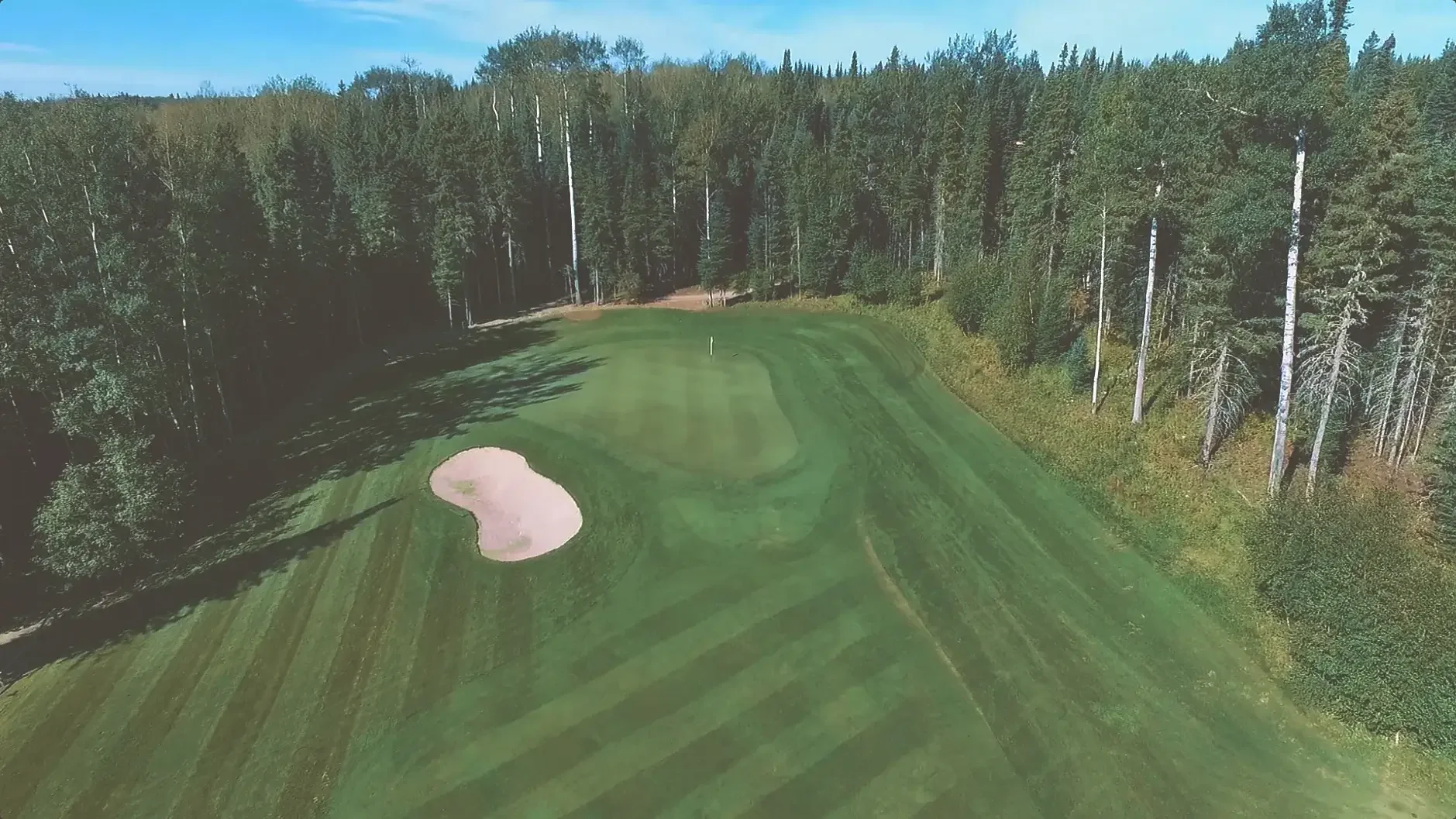 Aerial view of the fifth hole on the Aspen course at Elk Ridge Resort, a fairway winding through the boreal forest.