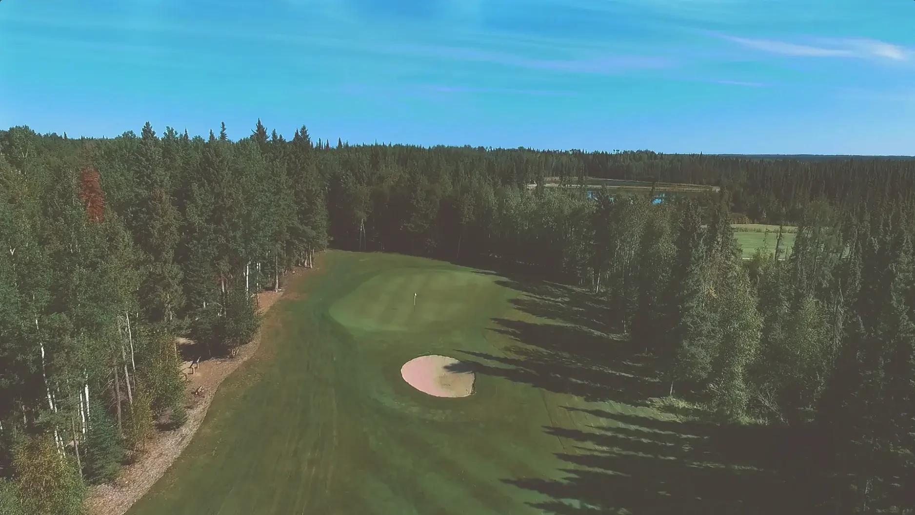 Aerial view of the seventh hole on the Aspen course at Elk Ridge Resort, a fairway lined with boreal forest.
