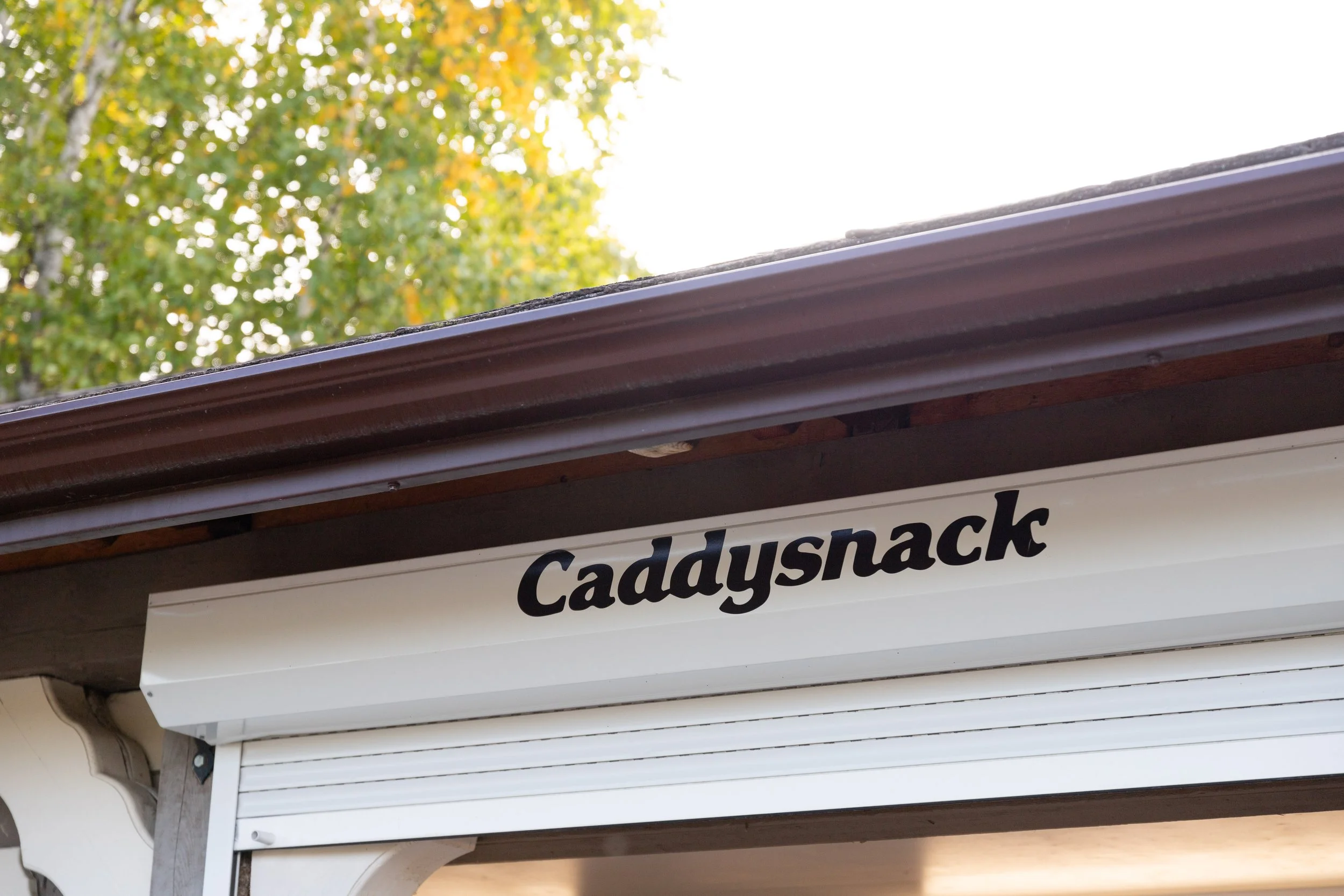 The Caddy Snack building under its roof, with trees behind it.