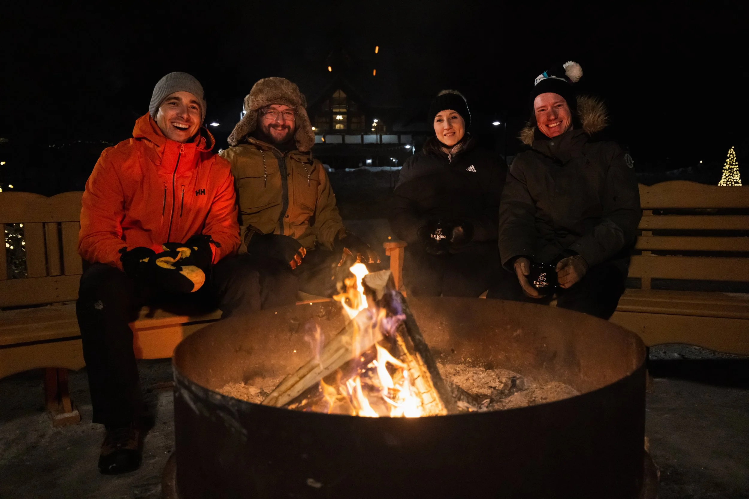 Four people sitting around a campfire at Elk Ridge Resort
