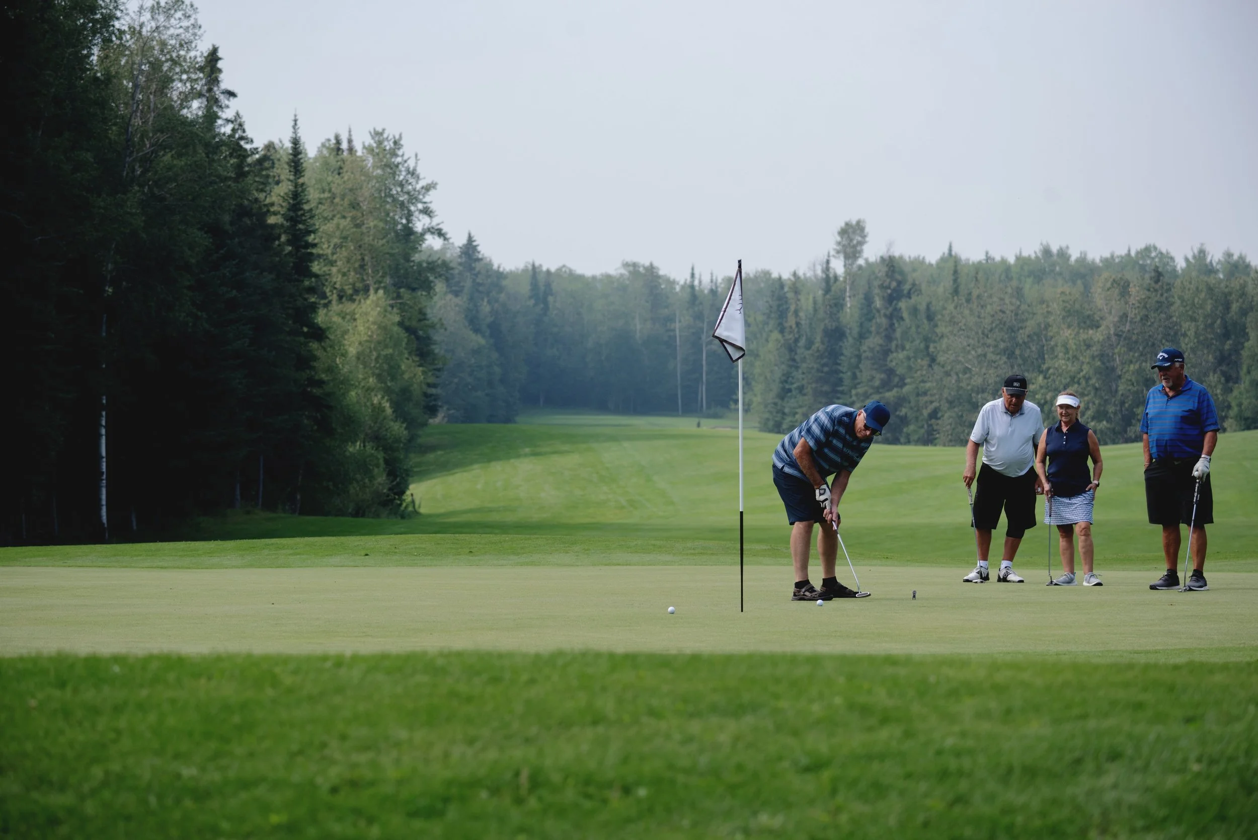 Four people playing golf on a lush green fairway