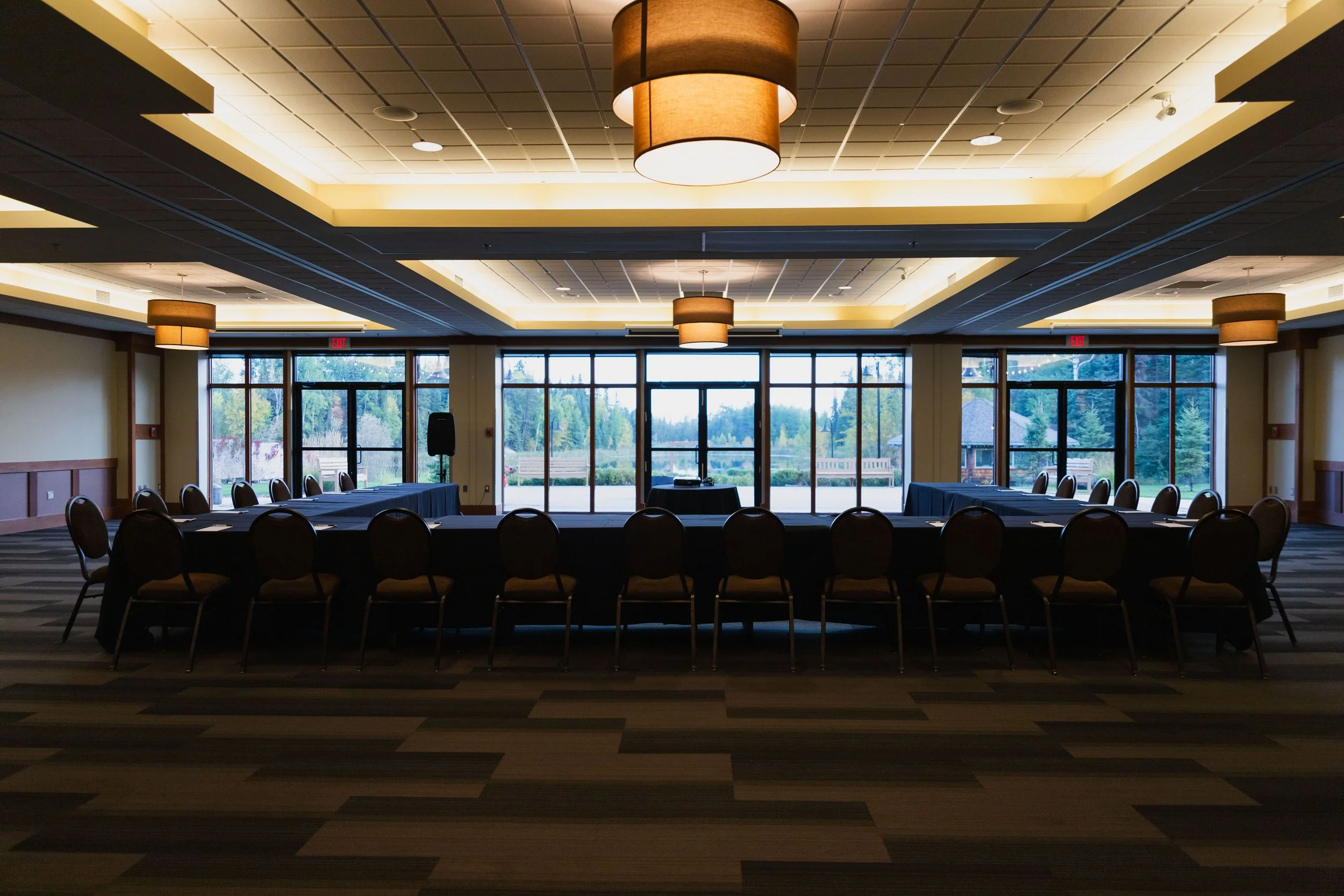 An empty conference room with dark tables set for a meeting