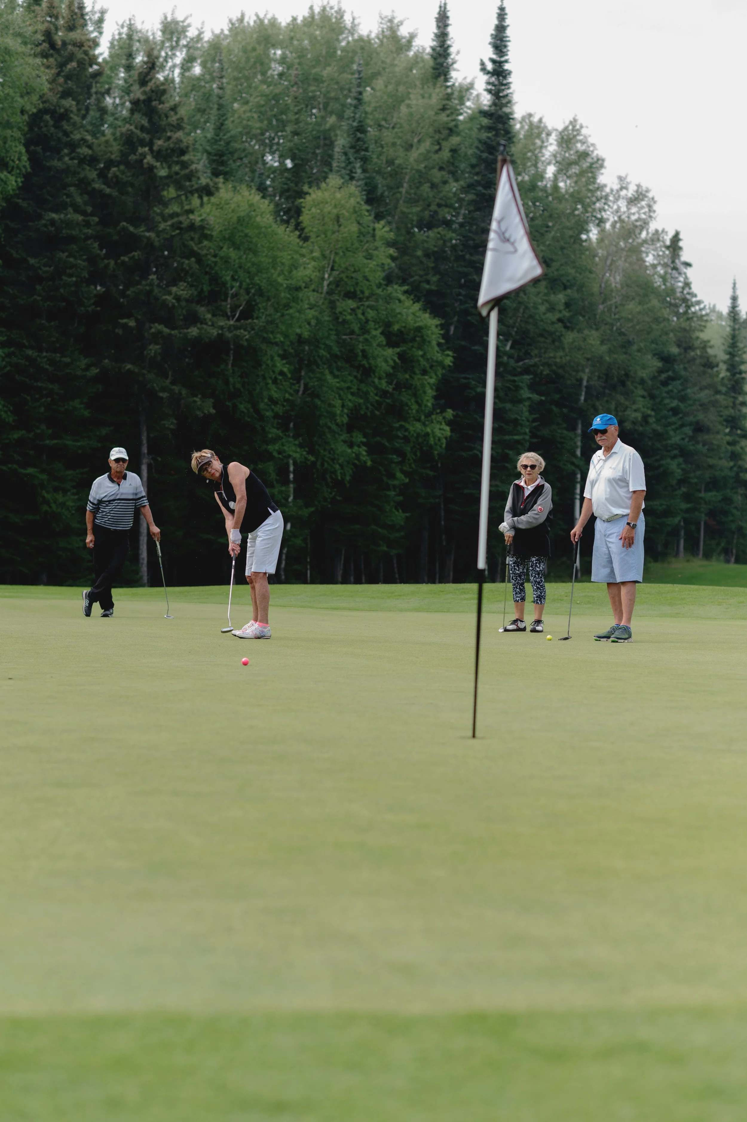 Four people playing golf on a green