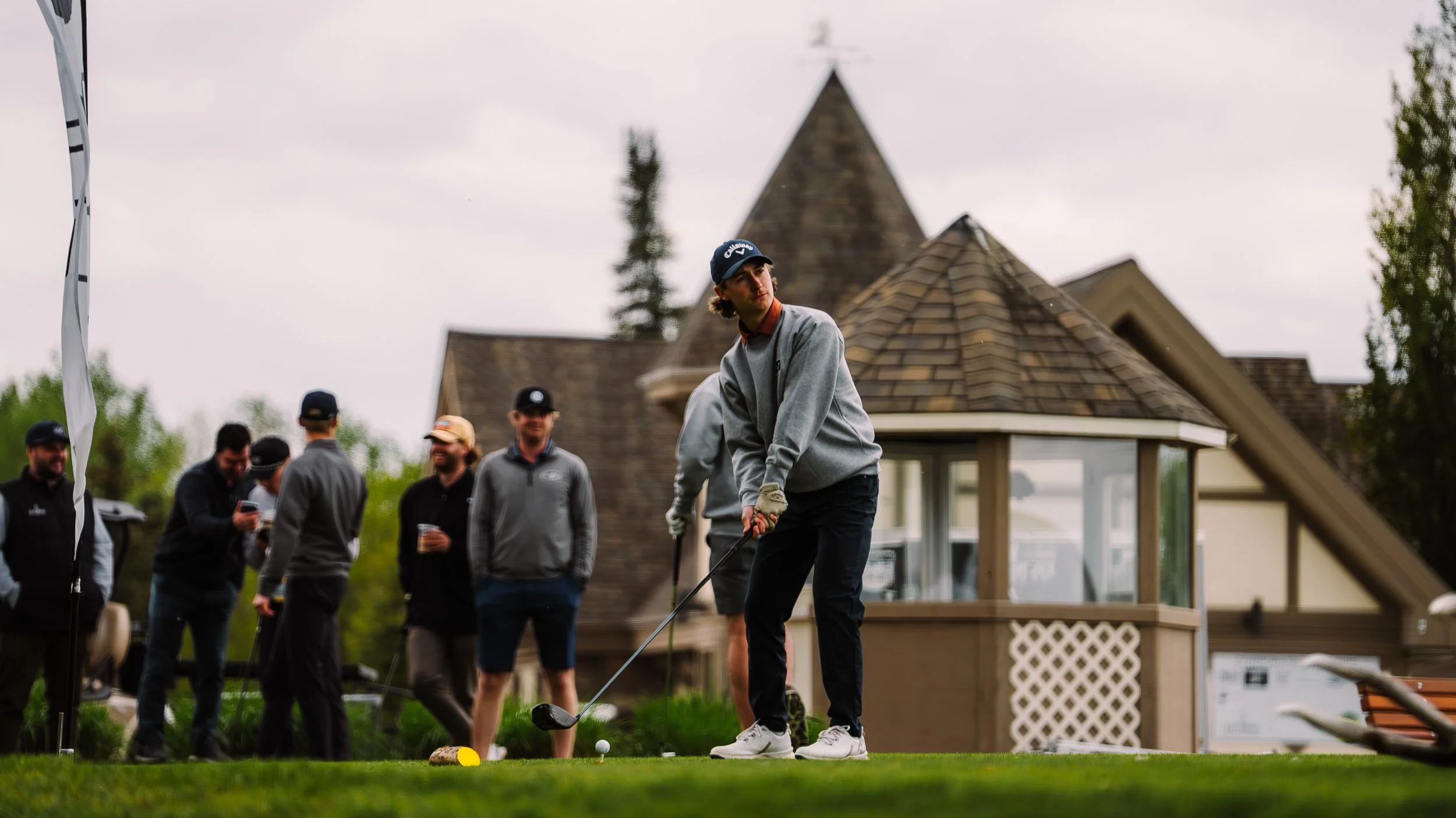 Group of people at a golf course, with one person preparing to take a shot near the hole.
