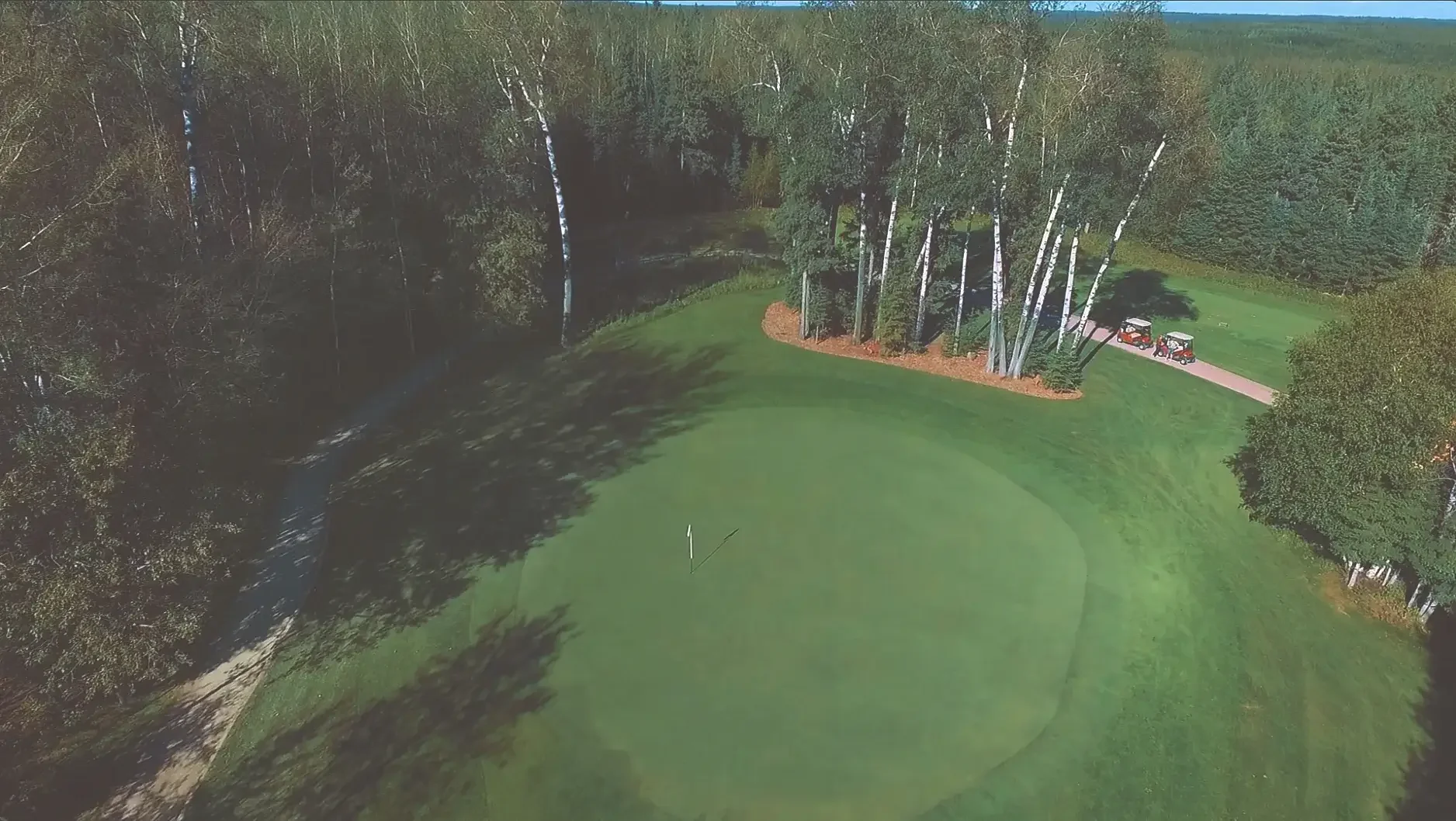 Aerial view of the fifth hole on the Tamarack course at Elk Ridge Resort, a fairway framed by boreal forest.