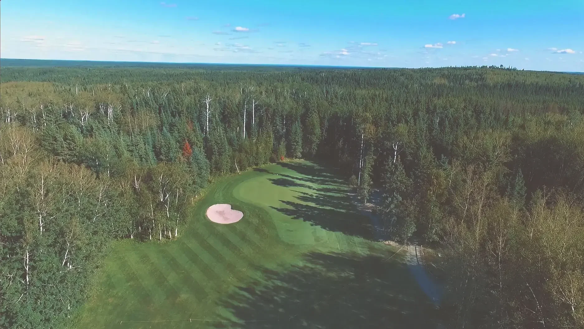 Aerial view of the sixth hole on the Tamarack course at Elk Ridge Resort, surrounded by trees.