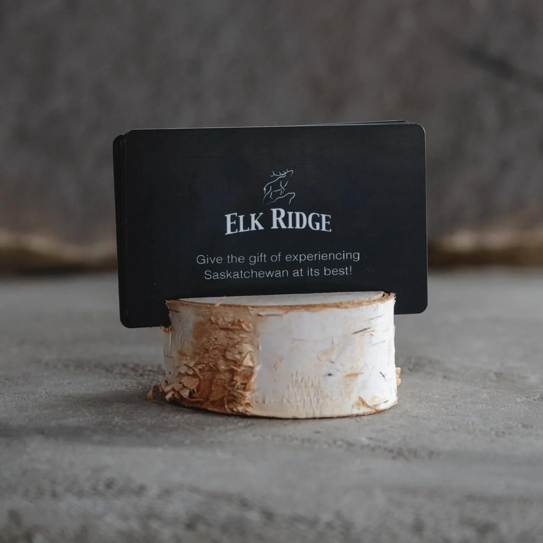 An Elk Ridge Resort gift card propped on a birch round