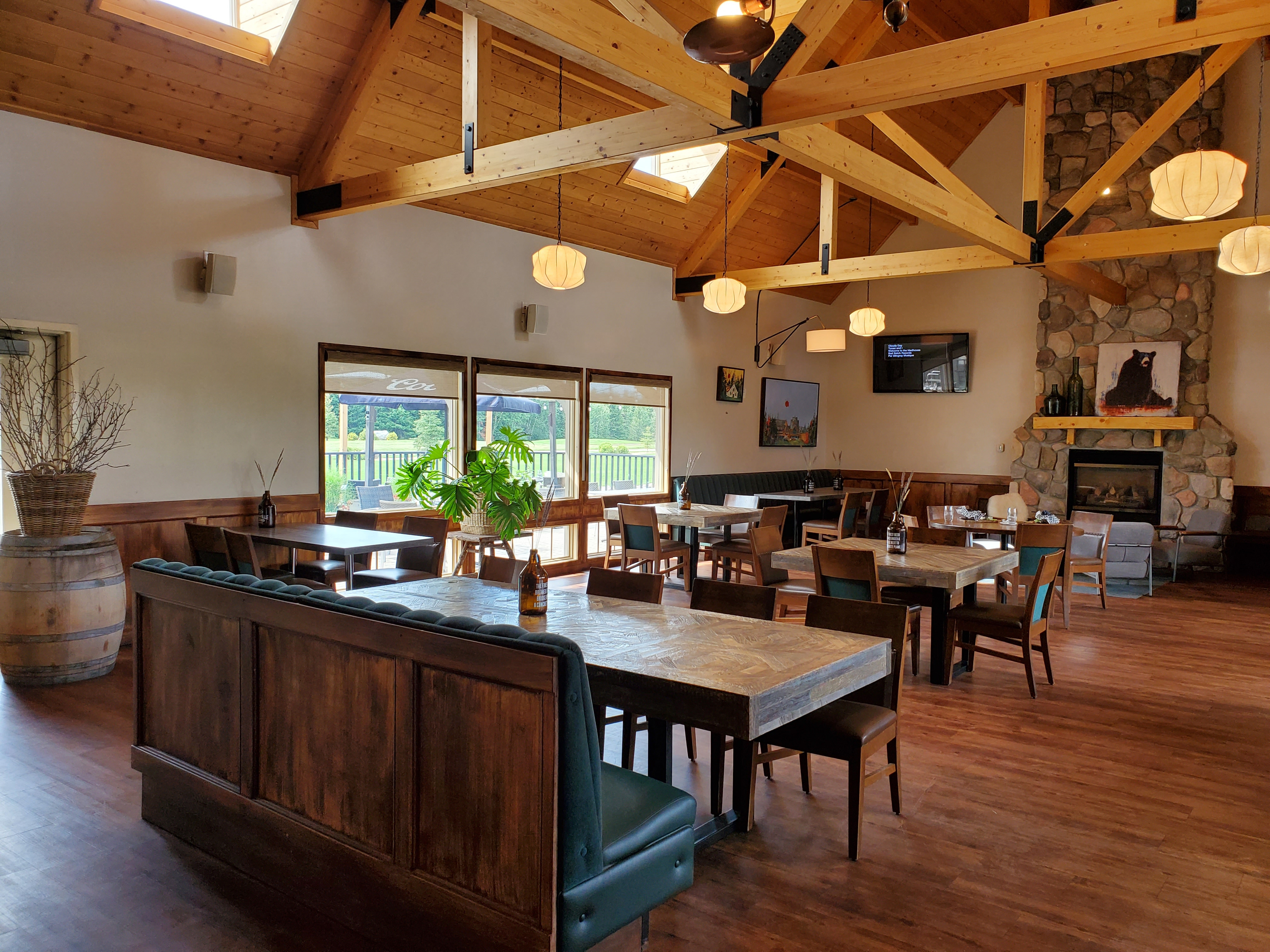 The dining room at the Wyld, with timber beams, a stone fireplace and tables set under pendant lights