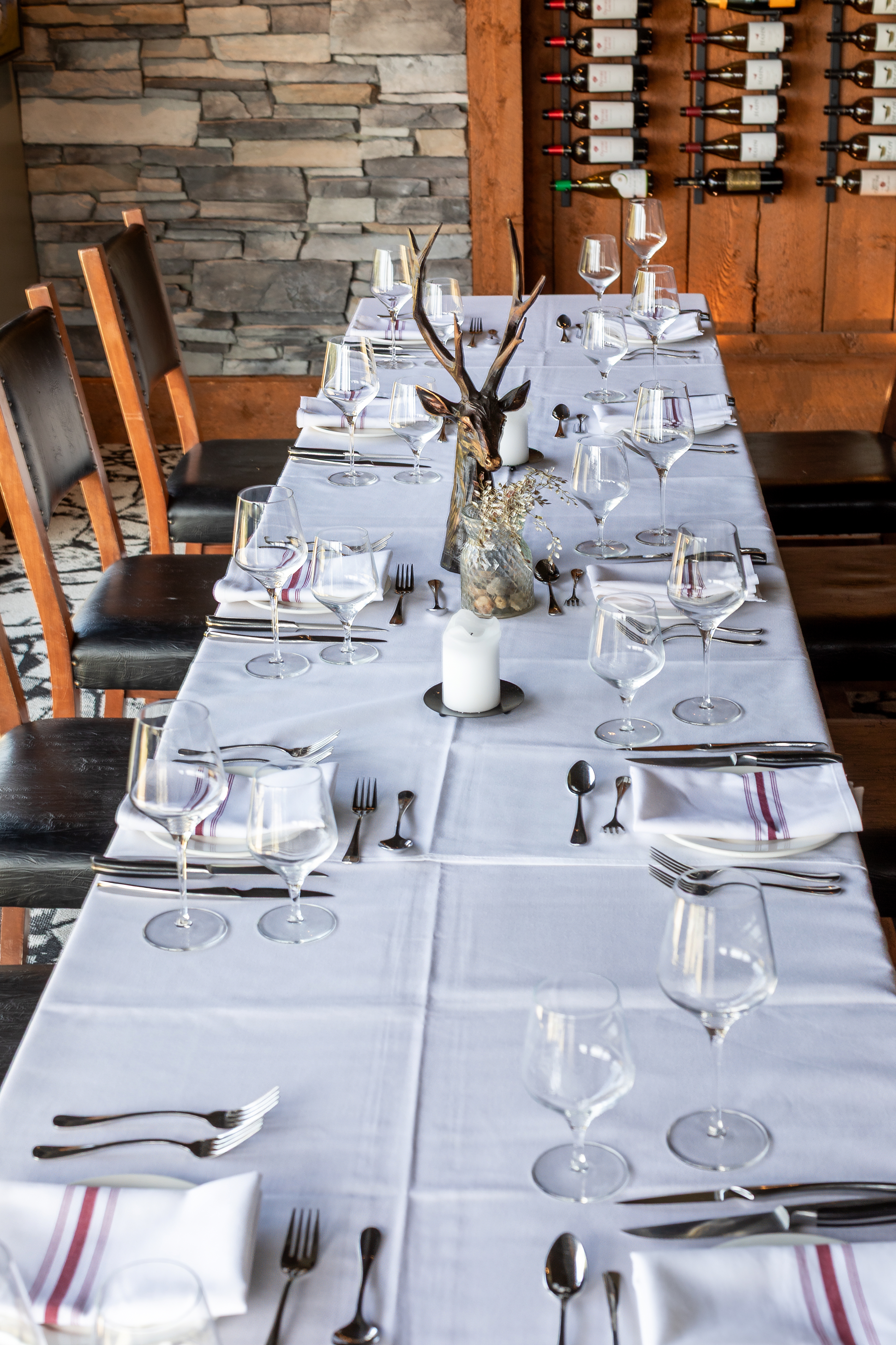 Long white-linen table set for dinner in the Wine Room at Fredrich, with an antler centrepiece